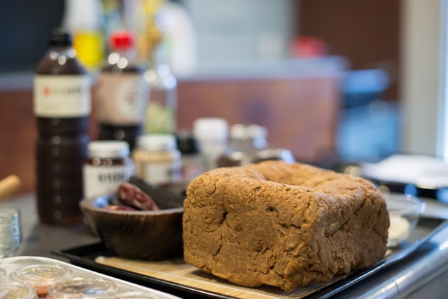 A dried meju block — a rough brown brick of fermented soybeans — on a tray in a kitchen.