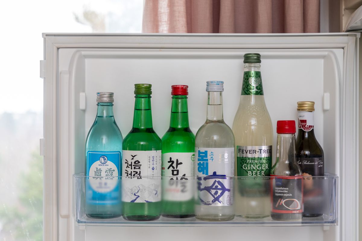 A refrigerator door shelf holding Korean soju bottles including Chamisul, Chum Churum, Jinro and Bohae, alongside a bottle of ginger beer.