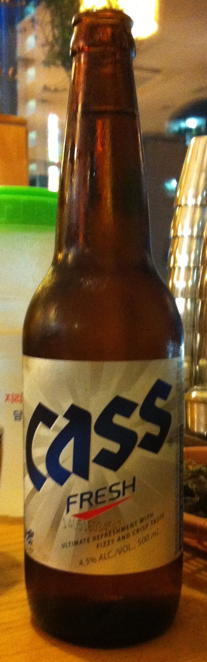 A bottle of Cass Fresh Korean lager on a table, its label showing 4.5% alcohol.