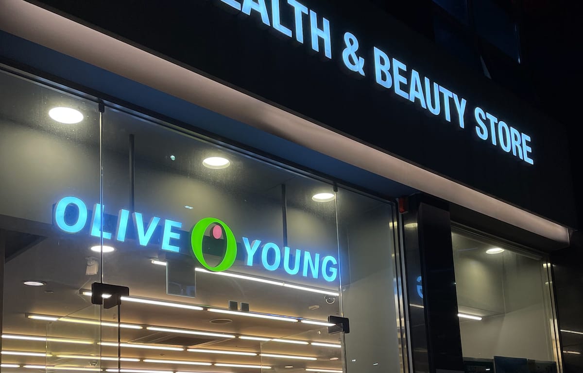 The illuminated shopfront of an Olive Young branch at night, signed OLIVE YOUNG and HEALTH & BEAUTY STORE.