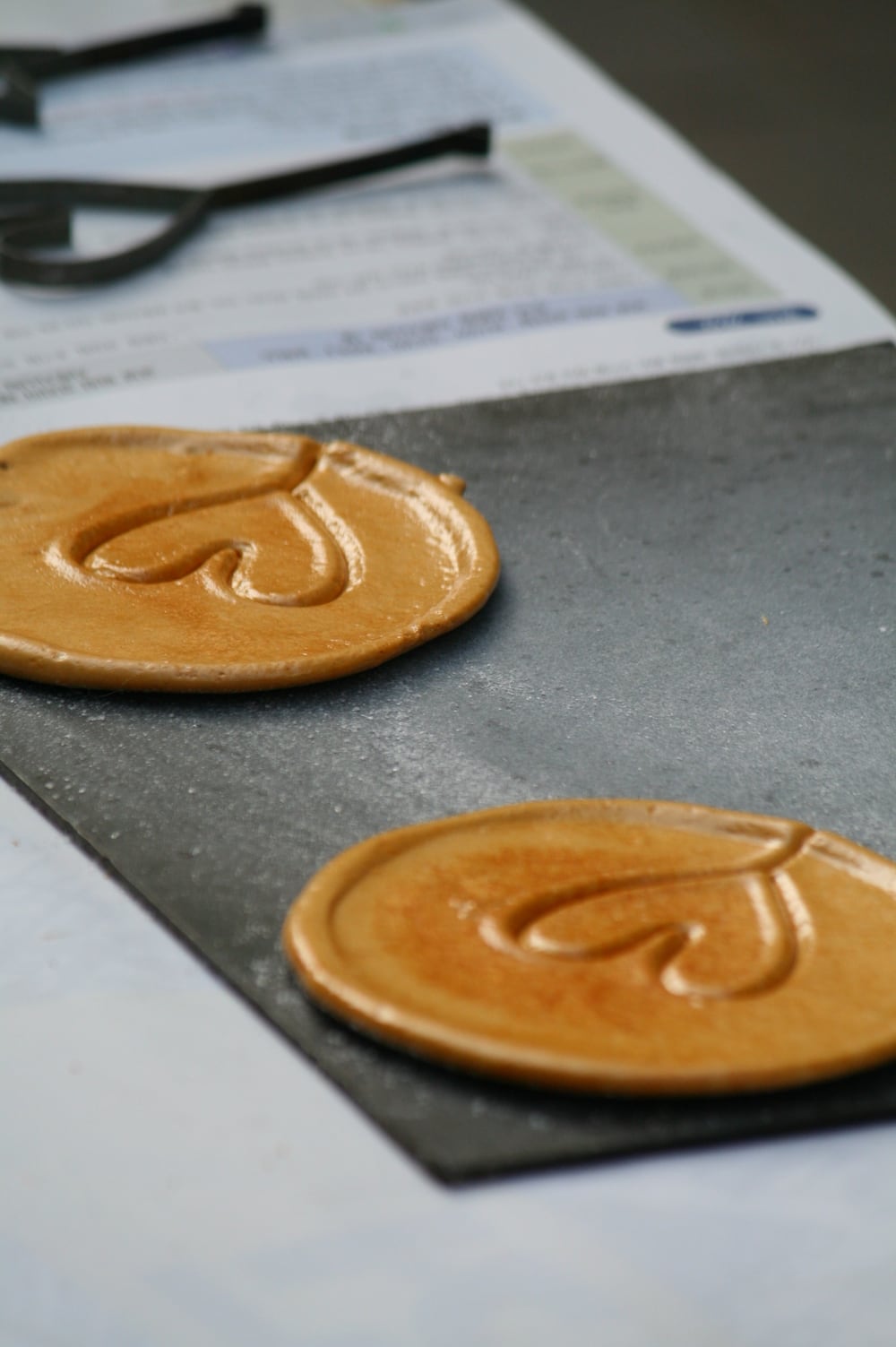 A heart-stamped dalgona candy on a dark tray.