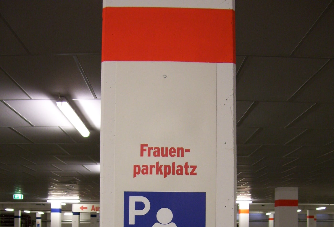 A Frauenparkplatz sign in a German multi-storey car park, red lettering above a blue women's pictogram.
