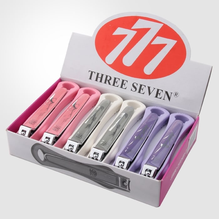 The red 777 logo and THREE SEVEN wordmark on a retail counter display box holding six pastel nail clippers in pink, grey and lavender.