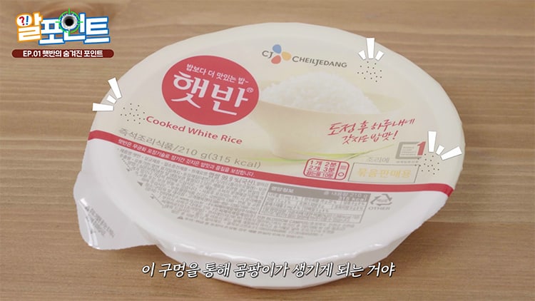 Top-down view of a Hetbahn 210 g bowl on a wooden table, showing the sealed lid film with the Korean cooking-instruction panel, from CJ's own consumer explainer video with Korean subtitles.