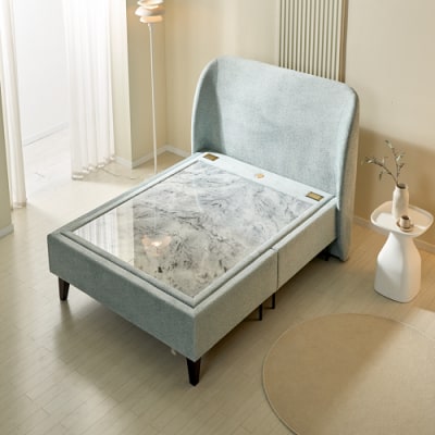 A modern Korean stone bed with an upholstered fabric headboard and a white marble sleeping surface.