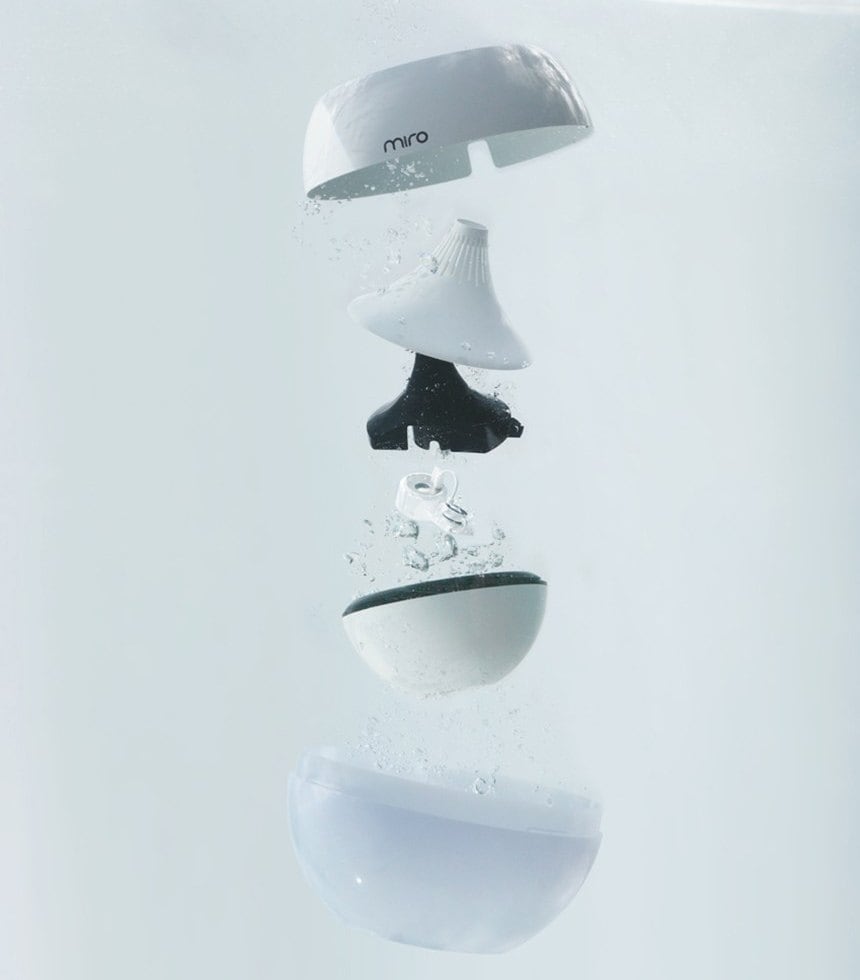 A Korean humidifier photographed underwater, separated into six distinct parts that float apart: the outer cap with the miro logo, the mist nozzle, a black inner housing, a small transducer component, the tank bowl and the base bowl.