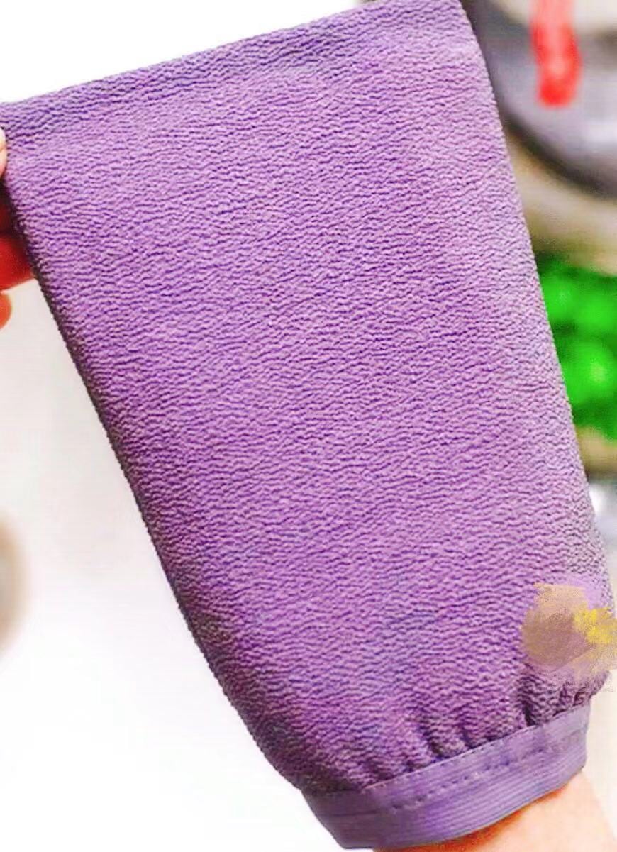 A purple Korean exfoliating mitt, the fabric visibly crinkled and coarse, held up in one hand.