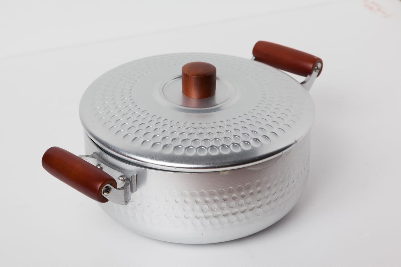 A Korean aluminium pot with a hammered finish, wooden side handles and a matching lid with a wooden knob, photographed against a plain white background.