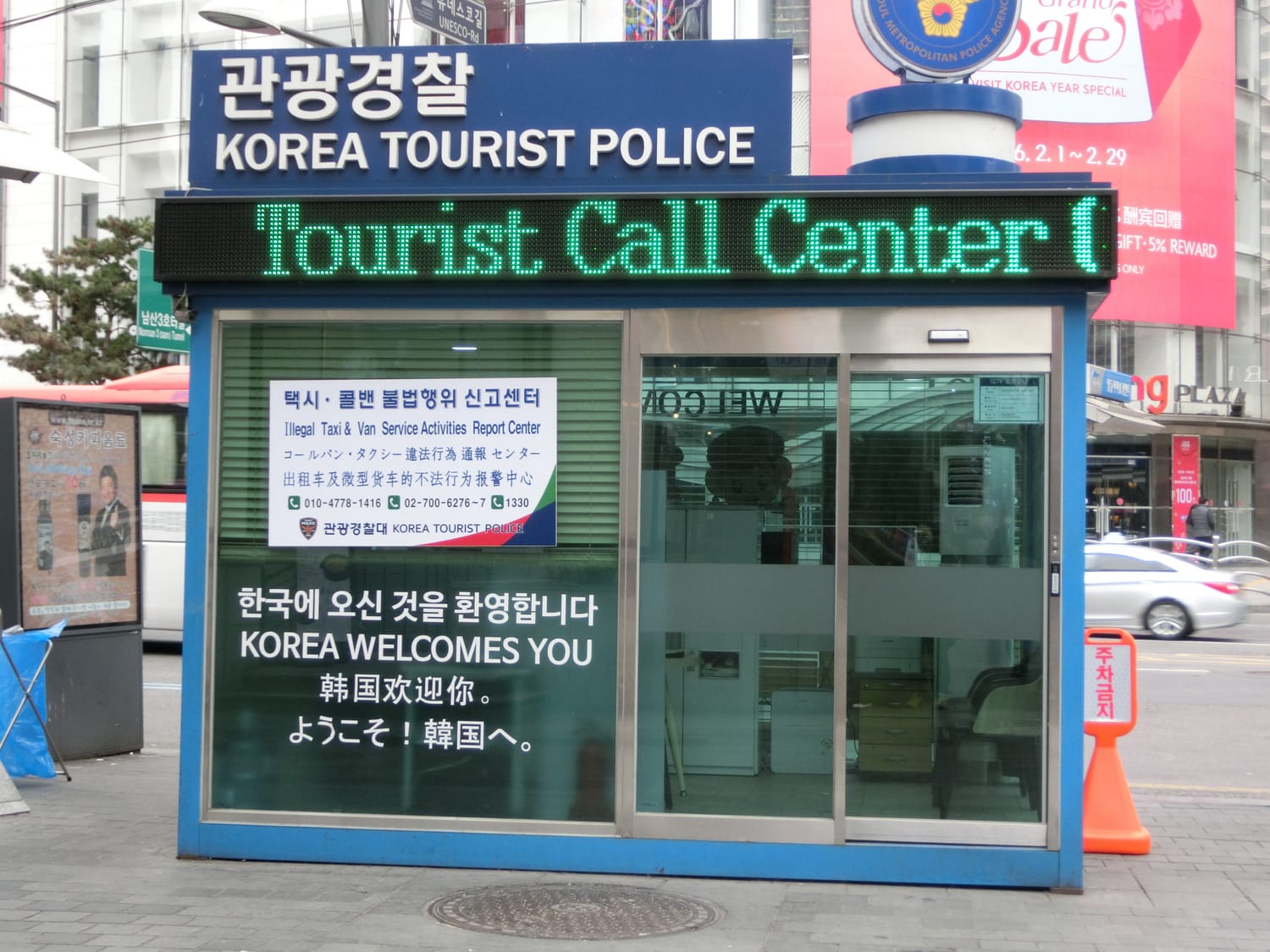 The Korea Tourist Police booth outside the Myeongdong Tourist Information Center, with a sign reading Tourist Call Center and a welcome message in Korean, English, Chinese and Japanese.