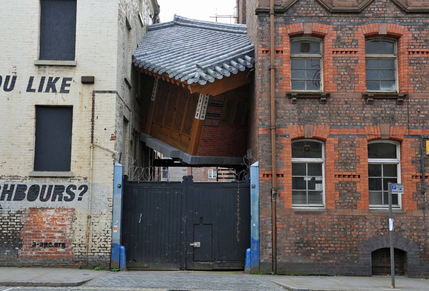 Do Ho Suh's Bridging Home, a full-size traditional Korean house wedged at an angle between two brick buildings on a Liverpool street.