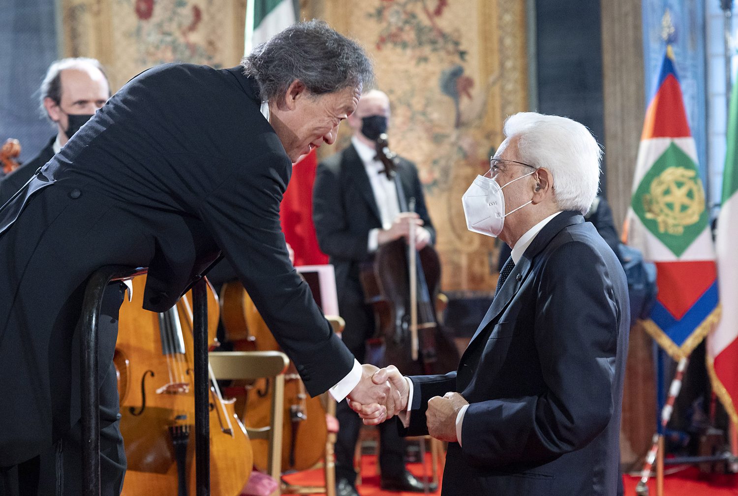 Conductor Myung-whun Chung, in tails, bending to shake hands with Italian President Sergio Mattarella beside the orchestra after a concert at La Fenice.