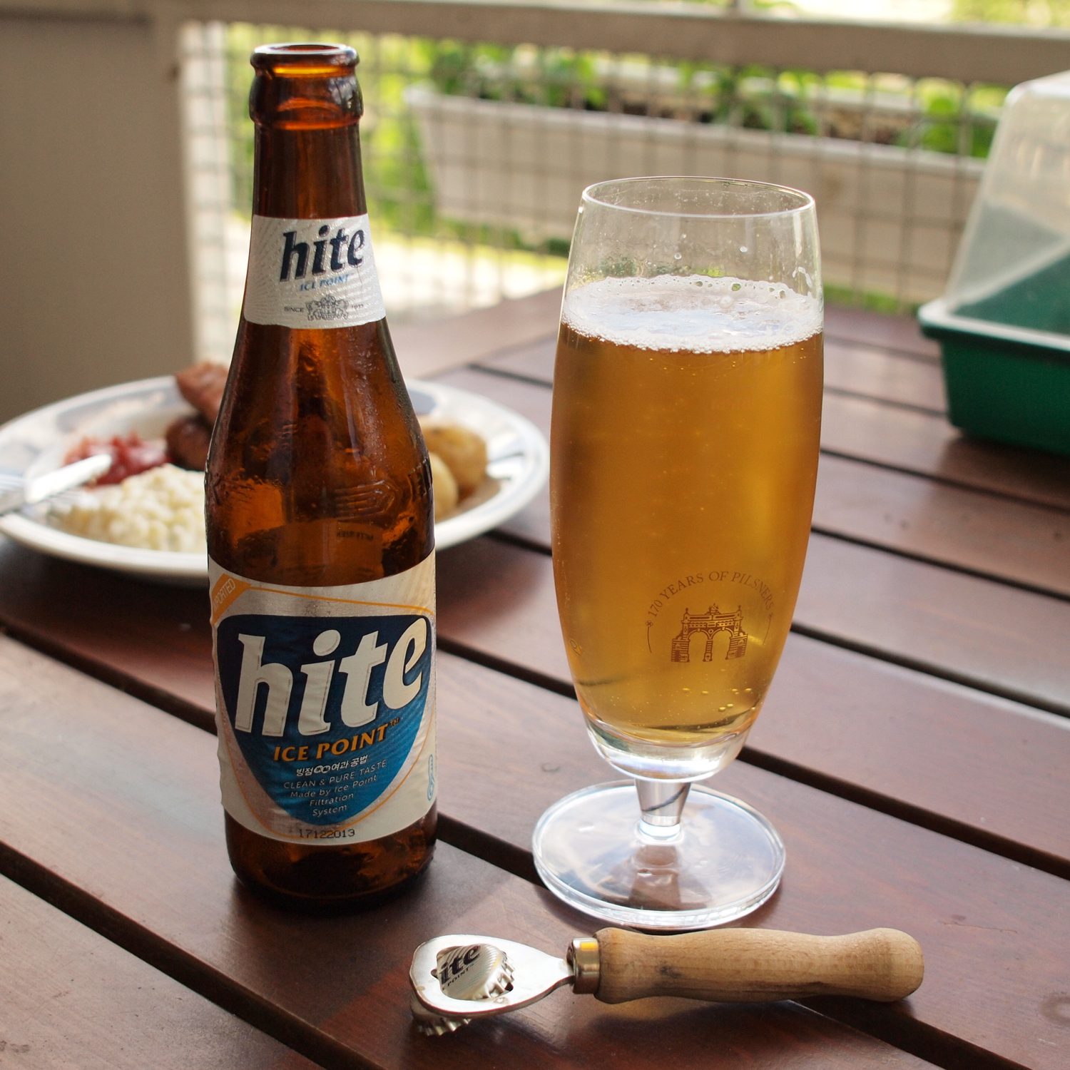 A bottle of Hite being poured into a tall pilsner glass on a wooden table, 2013.