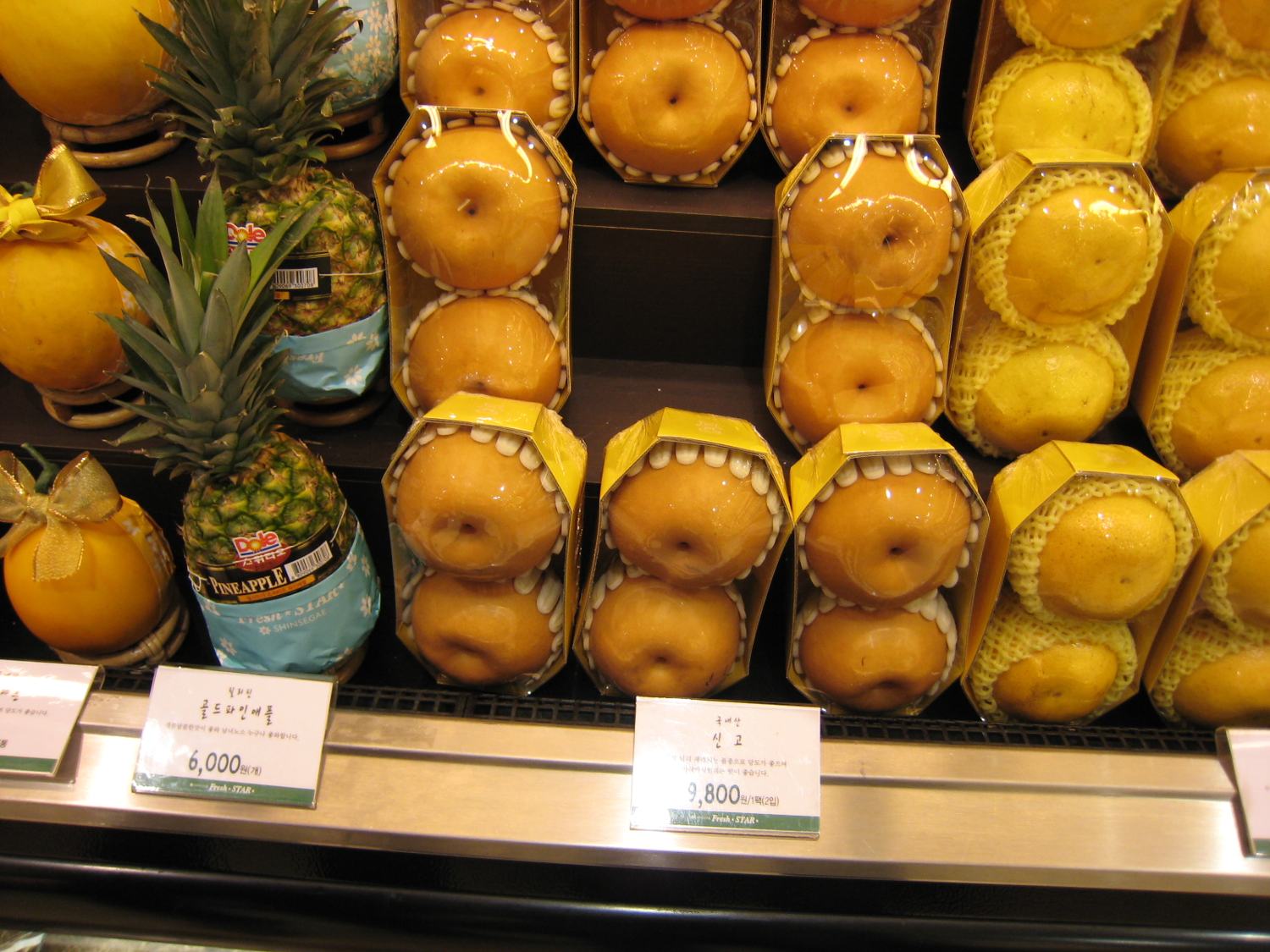 Boxed Singo pears in a Seoul shop, each pear in a white foam net, with price tags reading ₩6,000 and ₩7,800.