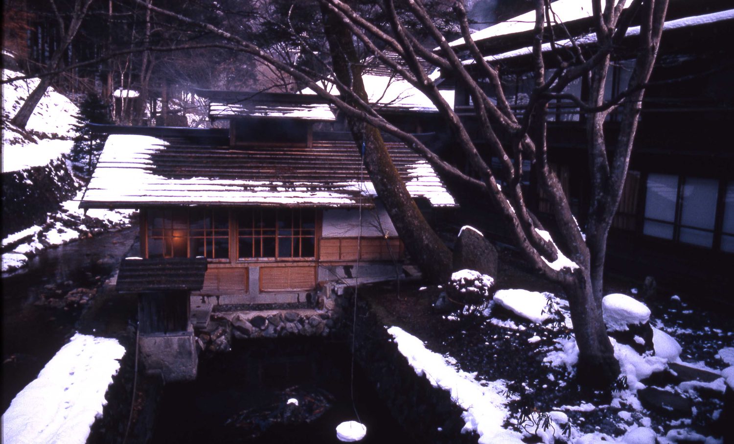 The stone outdoor bath at Hōshi Onsen ryokan in Gunma, Japan, under snow.
