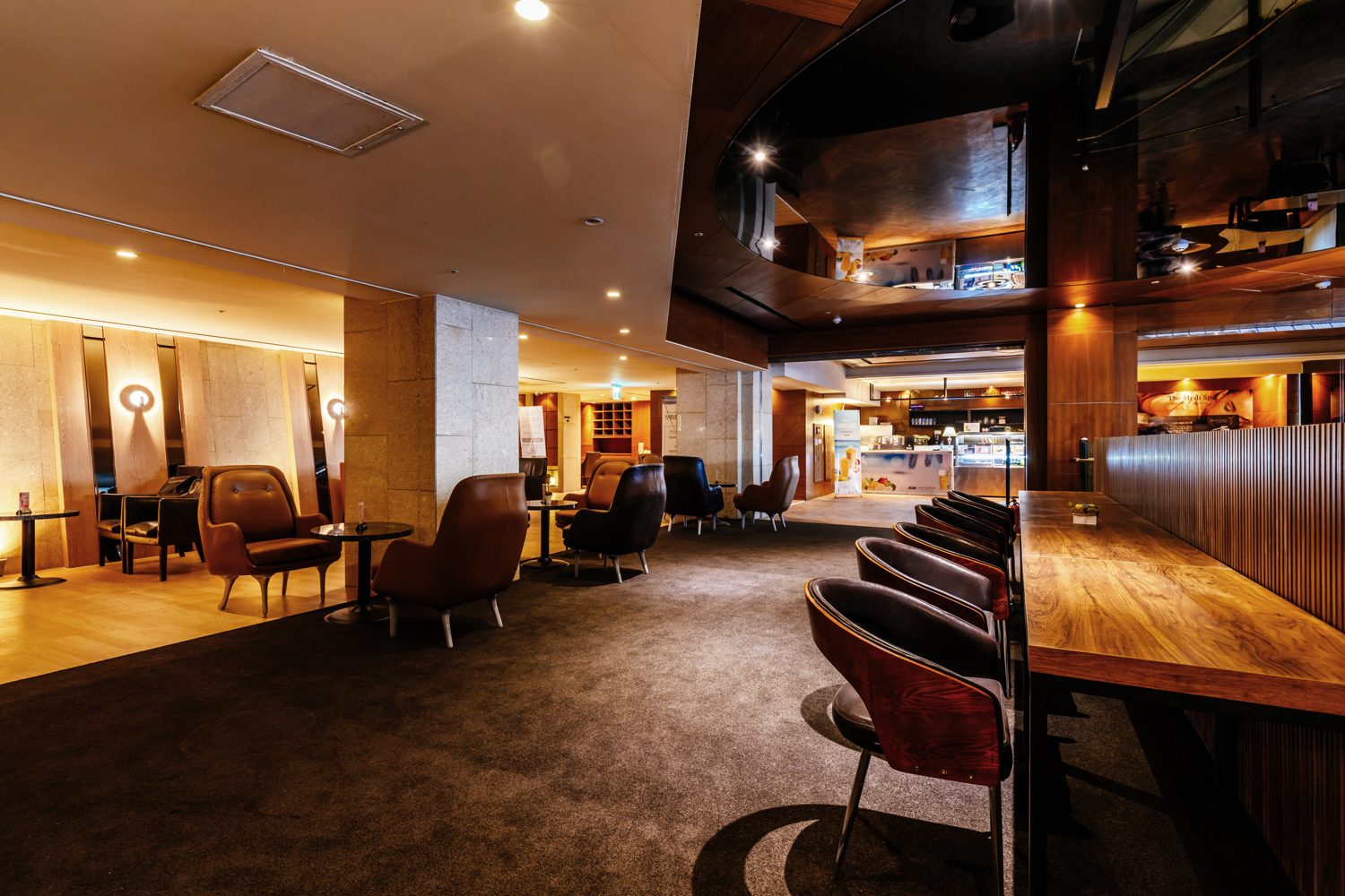 The members' lounge of The Riverside Hotel's Medi Spa: dark wood, leather armchairs, a long communal table under warm light.