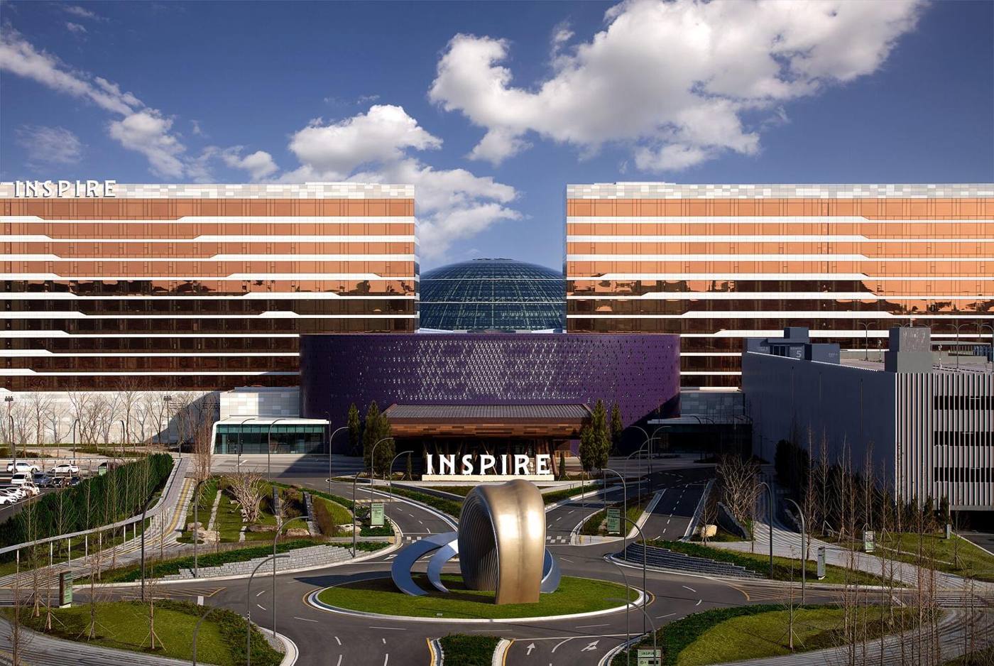 The exterior of Inspire Entertainment Resort near Incheon Airport: two copper-coloured hotel wings, a glass dome and a purple casino block.