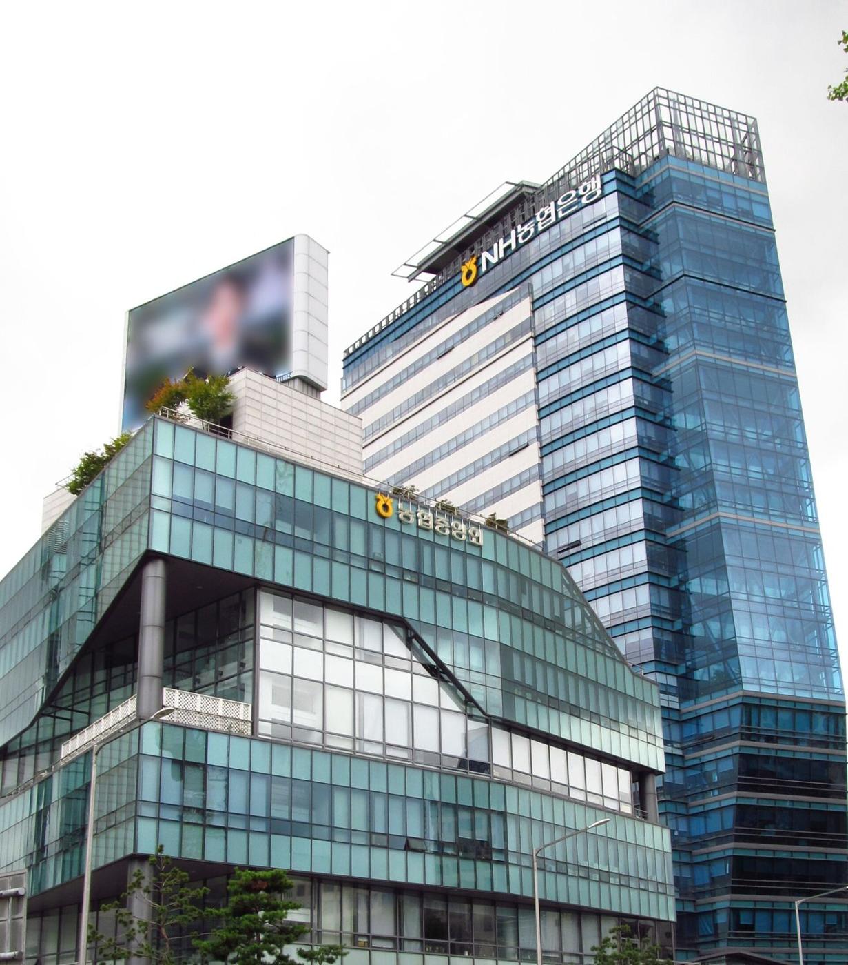 The headquarters of NH Bank in Seodaemun, Seoul, seen from the street: a glass tower with the NH농협은행 sign on top. Every Lotto 6/45 first prize in Korea is paid here.