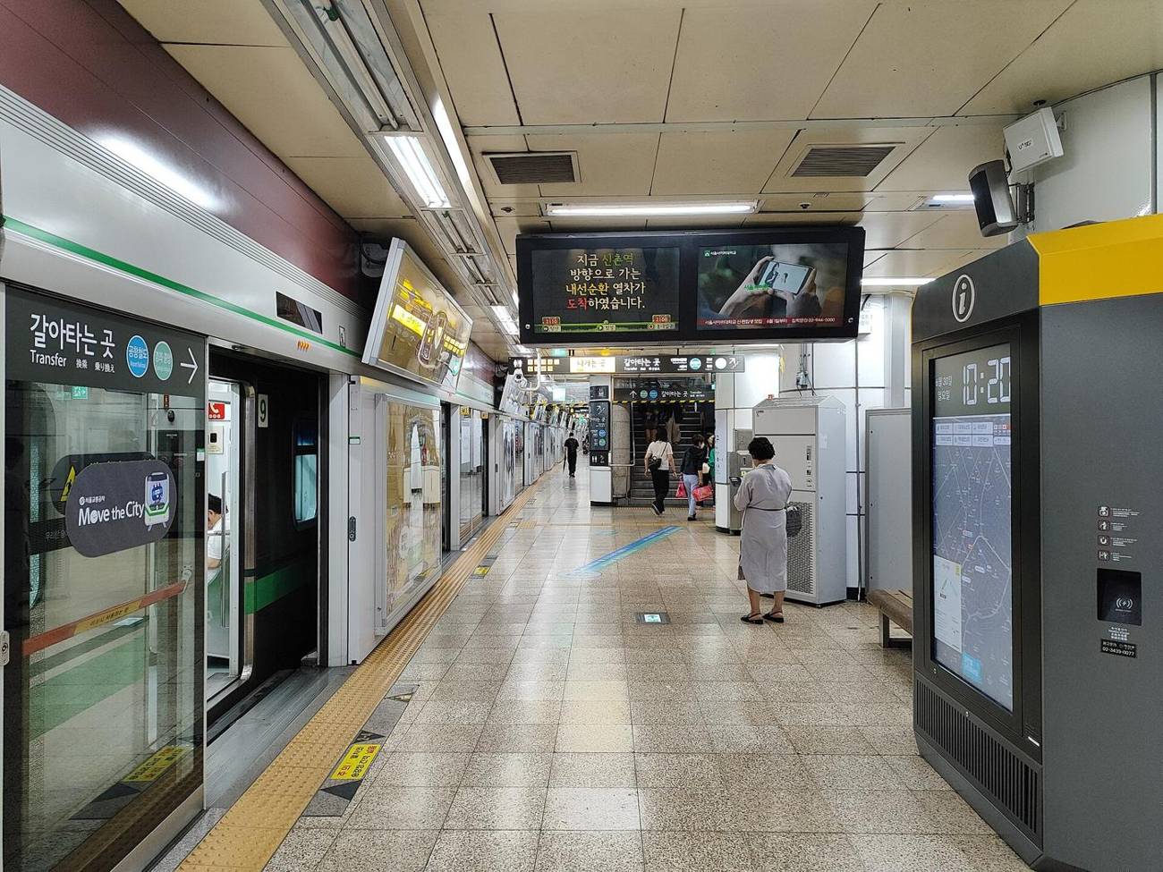 The Line 2 platform at Hongik University Station: a train at the screen doors, a transfer sign for the Airport Railroad and Gyeongui-Jungang Line, and an overhead display announcing an inner-circle train.