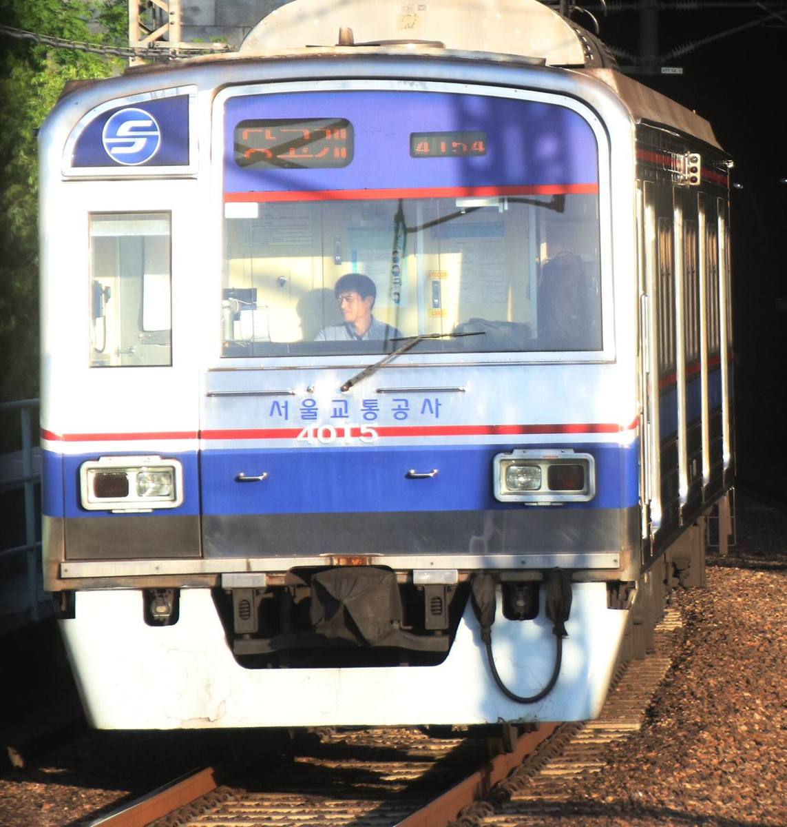 A Seoul Metro Line 4 train, blue-banded with 서울교통공사 on its front, emerging from a tunnel toward Dongjak.