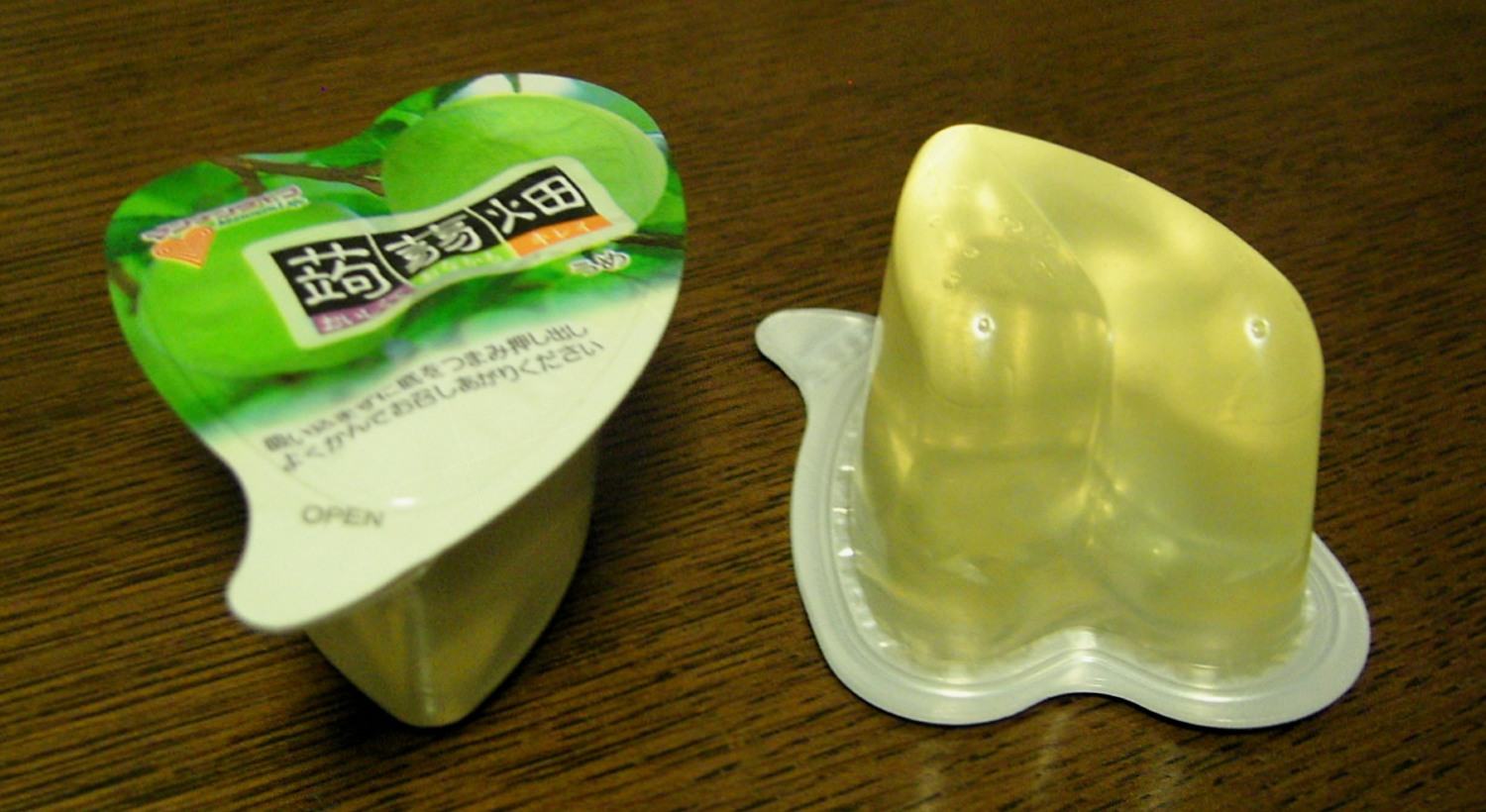 A green-and-white heart-shaped cup of Mannan Life konjac jelly next to the jelly tipped out of its cup.
