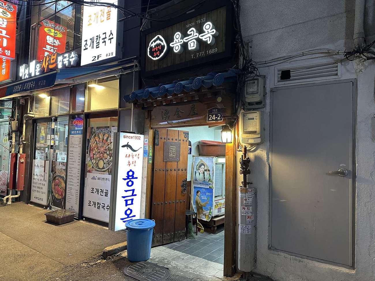 The narrow front of Yonggeumok in Da-dong under a blue-tiled eave, with its lit sign, a Seoul Future Heritage plaque and a wooden double door.