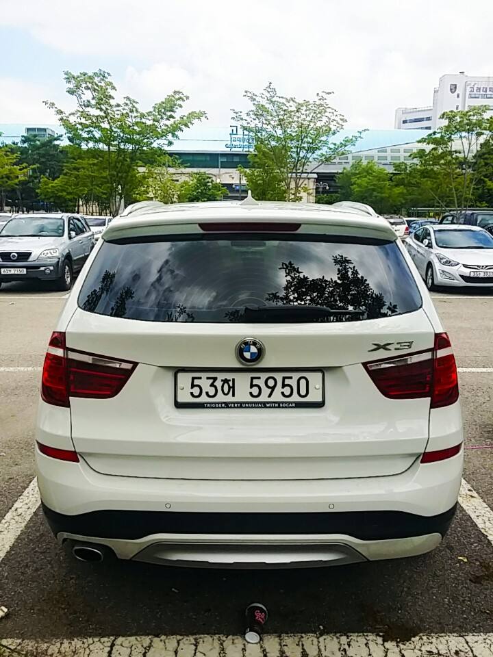 The rear of a white BMW X3 with a Korean rental plate and a Socar plate frame, in a car park.