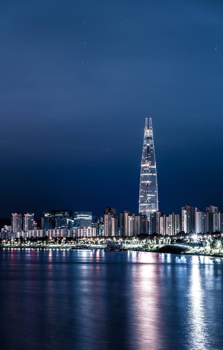 Seoul's skyline at night across the Han River, with Lotte World Tower lit in the centre.