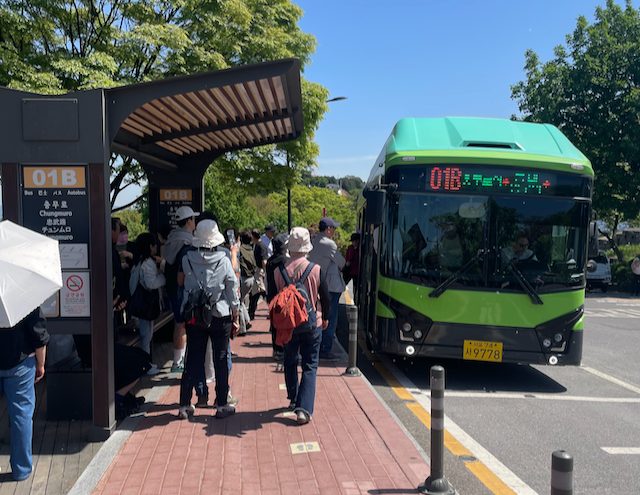 Visitors queuing at the Namsan Seoul Tower bus stop beside the 01B sign, with a green 01B bus to Chungmuro Station pulled in.