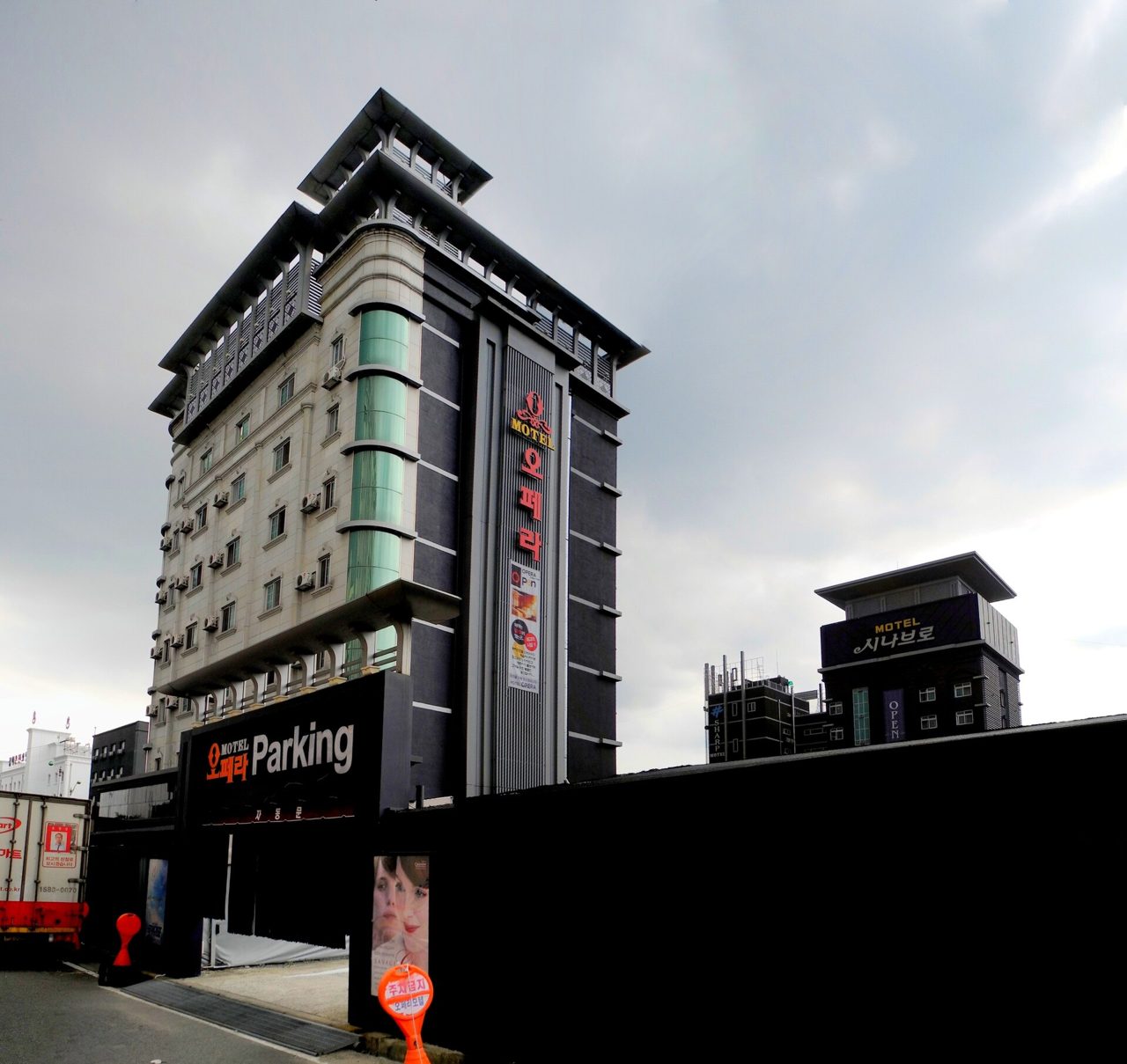 A tall motel building in Daejeon with a vertical sign and a screened parking entrance at street level.