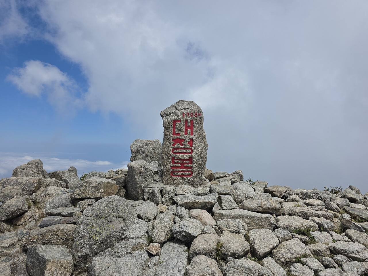 The summit stone of Daecheongbong on Seoraksan, carved with red Korean characters, standing among rocks.