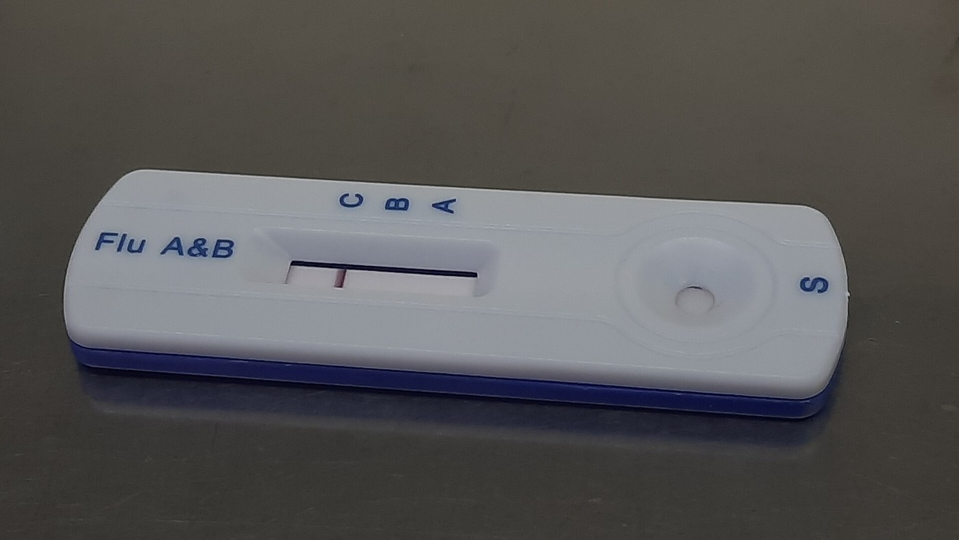 A white rapid-test cassette labelled Flu A&B with C, B and A markings above the result window; only one line is visible, and a sample well marked S sits on the right.