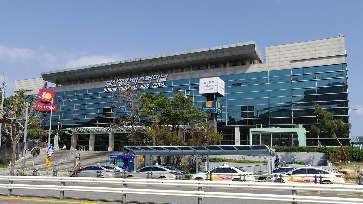 The glass-fronted Busan Central Bus Terminal with 부산종합버스터미널 and BUSAN CENTRAL BUS TERM. on the facade, taxis queuing under a canopy in front, April 2018.