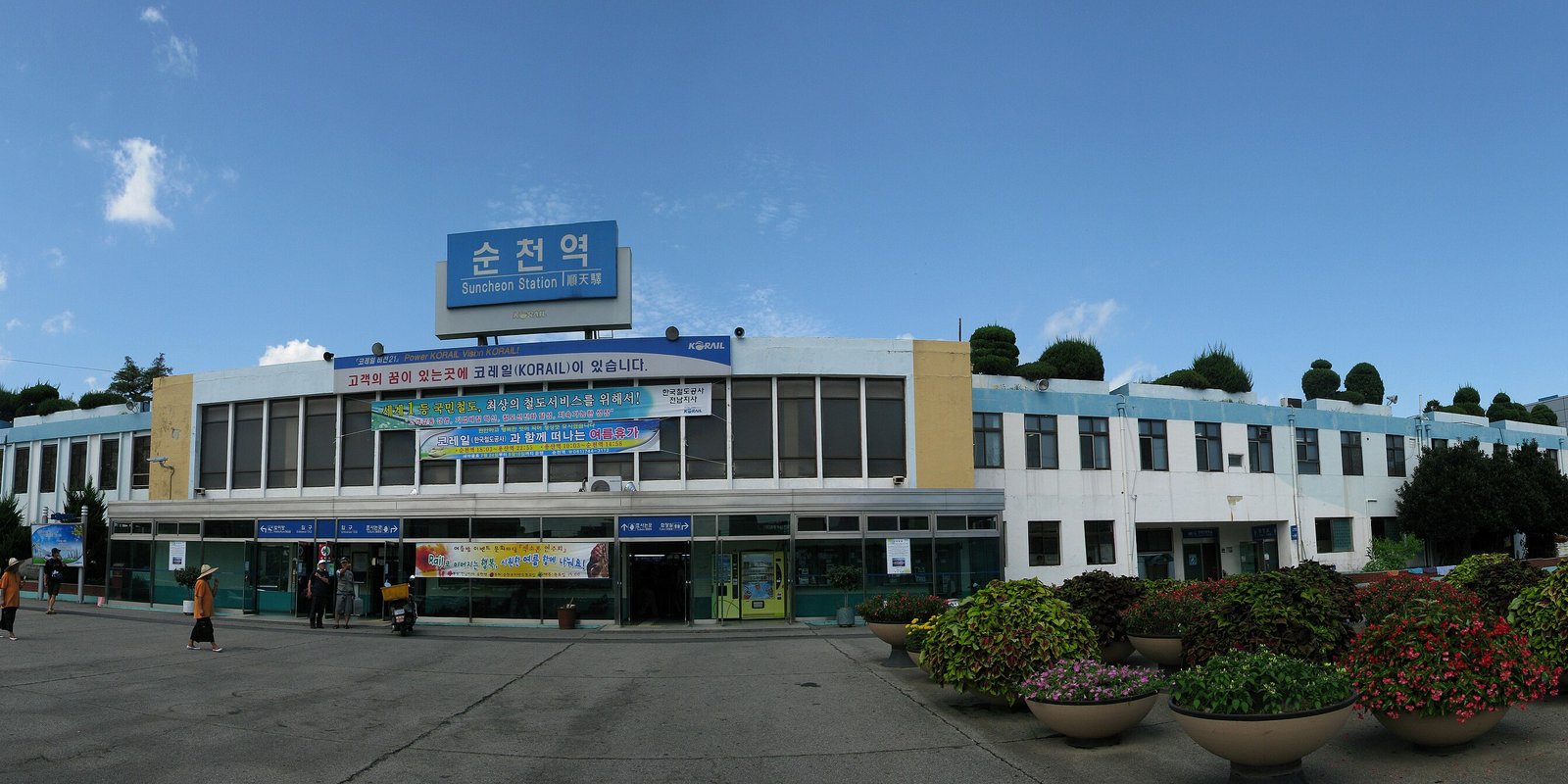 The front of Suncheon Station on the Jeolla and Gyeongjeon lines: a long two-storey building with a blue 순천역 sign on the roof and flower planters in the plaza, August 2009.