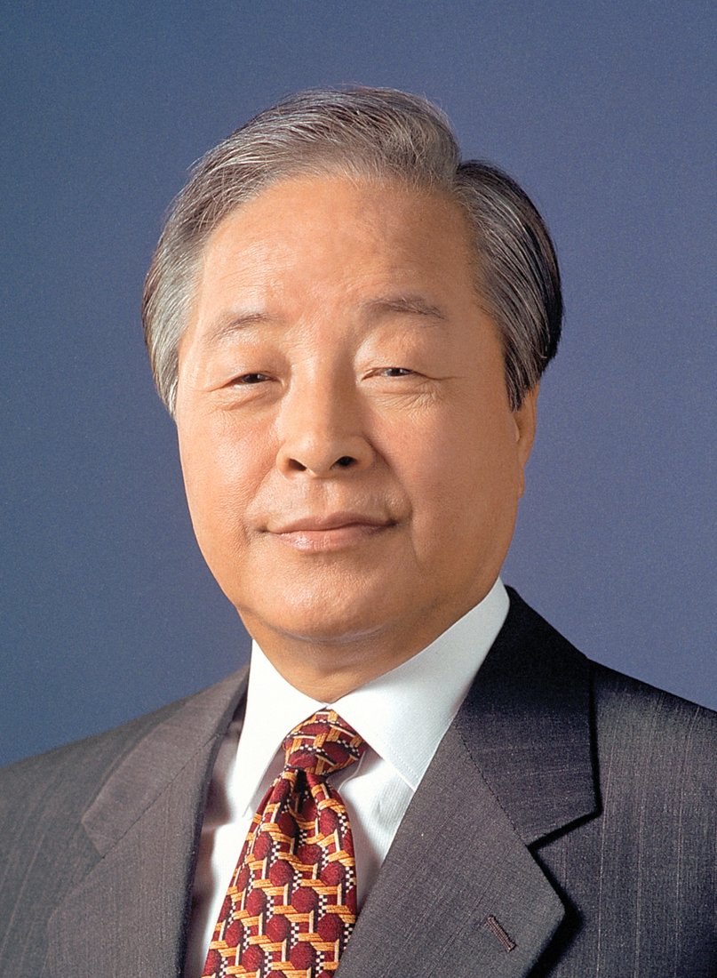 The official presidential portrait of Kim Young-sam: a grey-haired man in a dark grey suit, white shirt and red patterned tie, smiling slightly against a plain blue background, dated 25 February 1993.