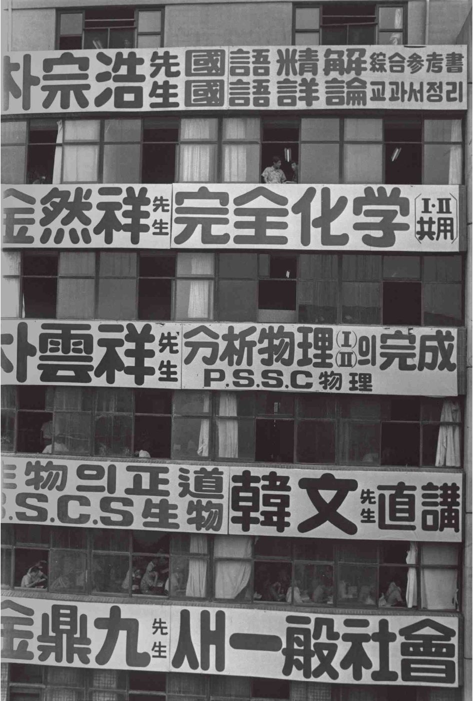 A black-and-white photo of a multi-storey cram-school building in Jongno, Seoul, in July 1971, its facade covered in large banners in Chinese characters and Korean advertising named teachers' Korean, chemistry, physics, biology and social studies courses.