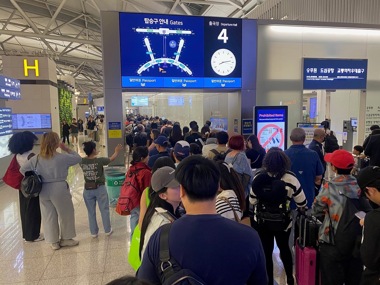 Incheon International Airport Terminal 1, departures level: travellers queue at the entrance to Departure Hall 4 under a screen that reads 탑승구 안내 Gates and 출국장 Departure Hall 4, with check-in row H marked by a large yellow letter on the left.