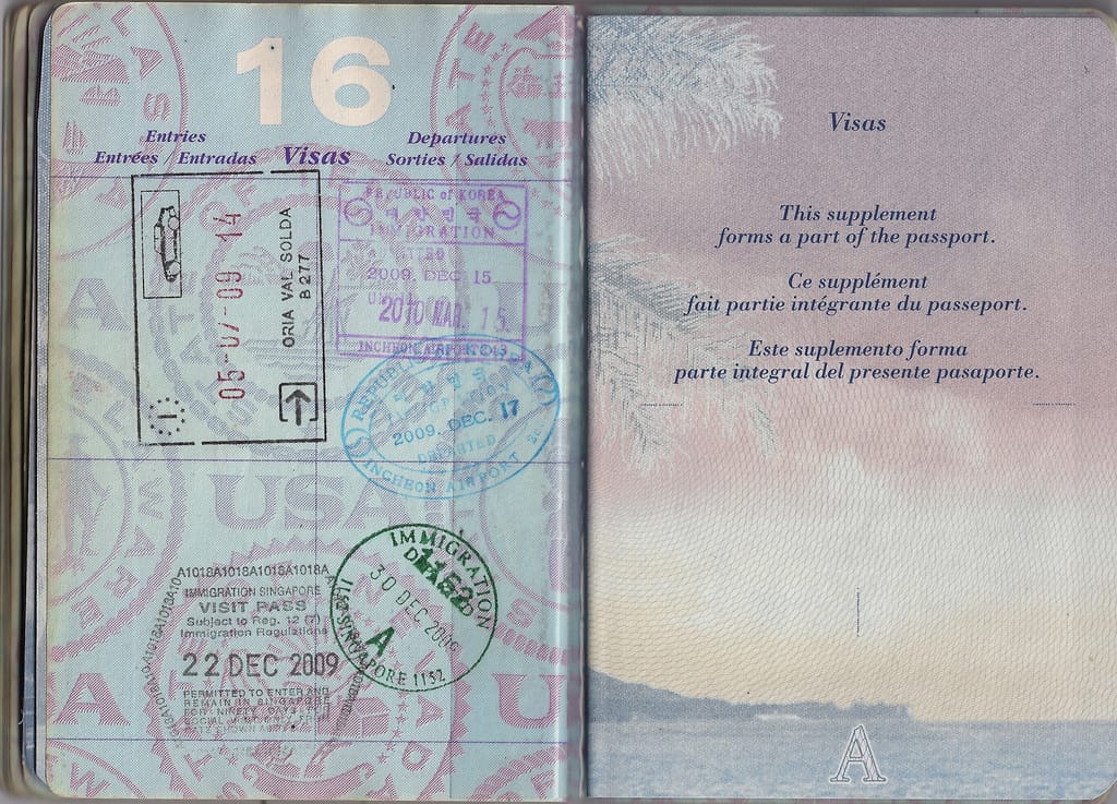A United States passport open at its visa pages, showing a purple Republic of Korea Immigration entry stamp from Incheon Airport dated 15 December 2009 and a blue departure stamp dated 17 December 2009, next to Italian and Singapore stamps.